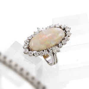 A FINE OPAL AND DIAMOND RING. 750 white gold, set with a big white cabouchon cut opal (c. 14,57 ct.), 6 Marquise cut diamonds and 20 brilliants (tog.c. 3,4 ct./w/si). RM 61. C. 15,3 gr.