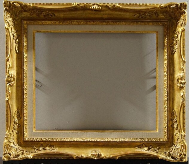 A Gilded Composition Louis XV Style Swept and Pierced Frame, late 20th century, with leaf sight, the plain hollow with foliate and flower head scroll work and shell cartouche corners, added parcel gilded and linen 39.8 x 46.4 cm (sight): together...