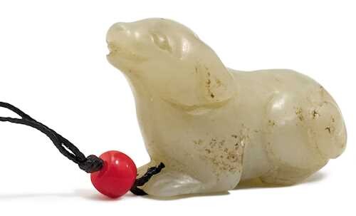 A JADE CARVING OF A SMALL RECUMBENT DOG.