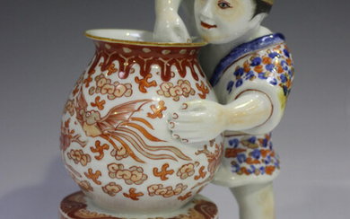 A Japanese Kutani porcelain figure group, Meiji period, modelled as a potter standing beside and wor