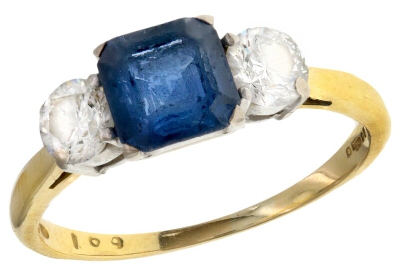 A Sapphire and Diamond Ring The emerald cut medium blue sapphire, flanked by two round cut diam...