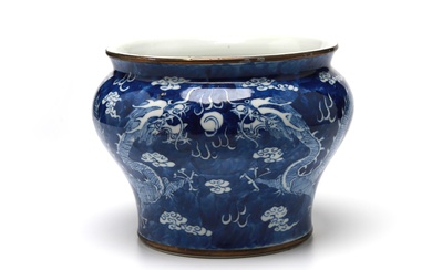 A blue and white porcelain spittoon painted with dragons writhing amidst clouds on a blue ground