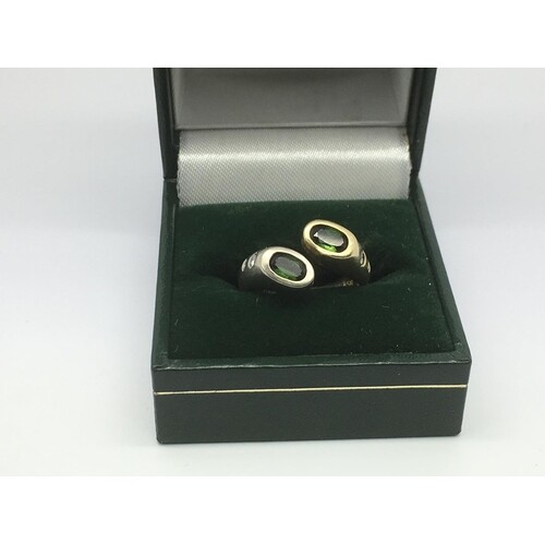 A modern design ring set with two green stones and small dia...