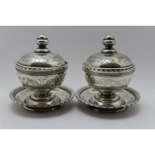 A pair of Middle Eastern white metal covered bowls on dish b...