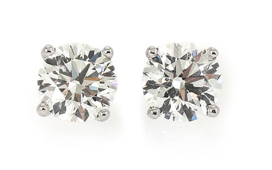 A pair of solitaire diamond ear studs each set with a diamond...