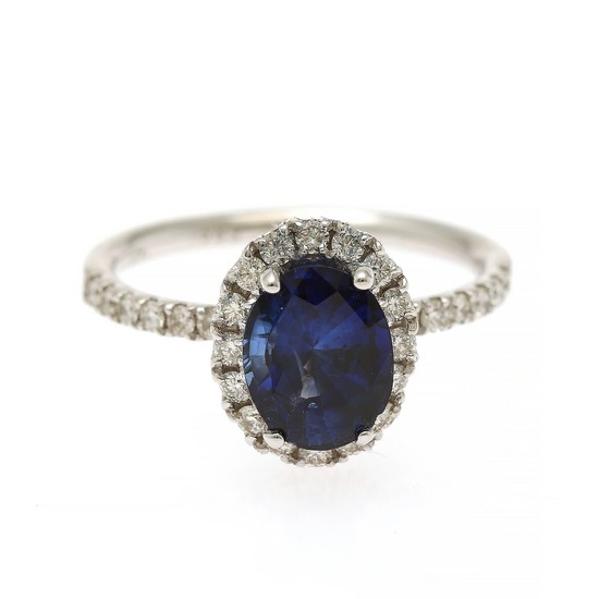 A sapphire and diamond ring set with an oval-cut sapphire and numerous brilliant-cut diamonds, mounted in 14k white gold. Size 55.