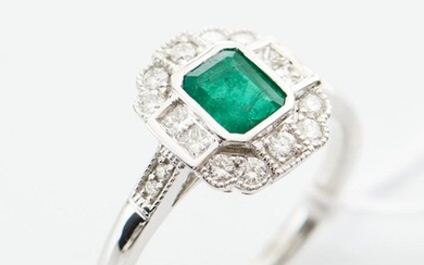 AN EMERALD AND DIAMOND DRESS RING IN 18CT WHITE GOLD, CENTRALLY SET WITH AN EMERALD CUT EMERALD ESTIMATED 0.75CT, WITHIN A SURROUND...
