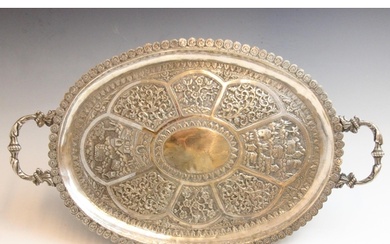 An Indian silver coloured tray, the cast twin handles above ...