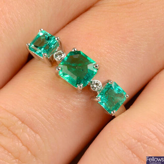 An emerald three-stone ring, with brilliant-cut diamond spacers.