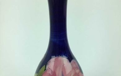 Moorcroft pottery slender neck vase decorated in the Magnolia pattern on blue ground, impressed marks and green painted signature to base, 27cm high