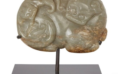 Property of a Gentleman (Lots 55-80) A Chinese celadon and russet jade 'Buddhist lion' dish, Ming dynasty, 17th century, carved to the underside with a recumbent Buddhist lion and a cub on her back, 7.5x12cm, later wood stand 明 十七世紀 青玉佛獅擺件 來源：紳士私人收藏