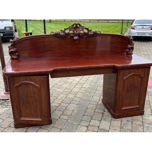A 19TH CENTURY MAHOGANY CARVED SIDEBOARD, with a shaped carv...