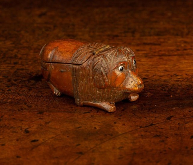 A 19th Century Treen Snuff Box naively carved in the form of a reclining dog with inset bead eyes an