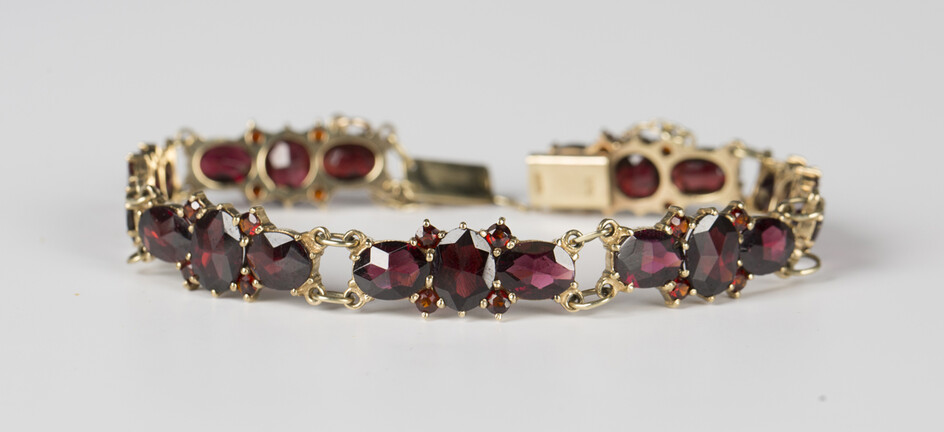 A 9ct gold and garnet bracelet, each link claw set with three oval cut garnets and four smaller circ