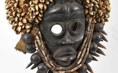 A Dan, Ivory Coast, mask adorned with cowry shells, bells...