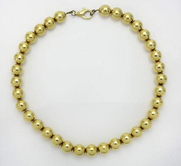 A bead necklace, composed of a uniform row of polished beads, stamped 18kt, length 42cm, gross weight approximately 64g