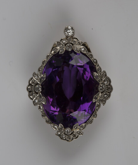 A gold, platinum, amethyst and diamond clip, mounted with the large oval cut amethyst within a diamo