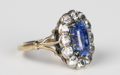A sapphire and colourless gem set oval cluster ring, claw set with the oval cut sapphire within a co