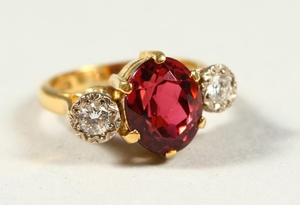 AN 18CT GOLD THREE STONE DIAMOND AND RED STONE RING.