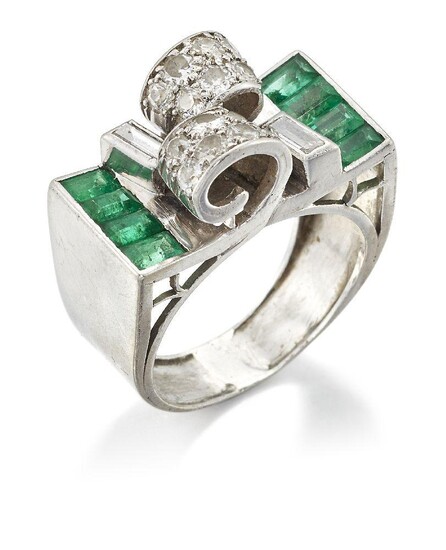 An Art Deco emerald and diamond ring, of Odeonesque design, the centre with pave diamond twin crossover scrolls with baguette diamond single stone detail and calibre emerald three stone shoulders, to a tapering hoop, c. 1935, ring size M
