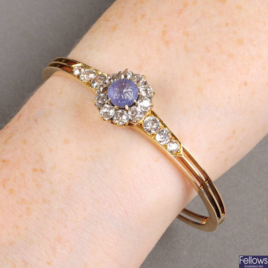 An early 20th century gold, foliate carved sapphire and old-cut diamond cluster hinged bangle.