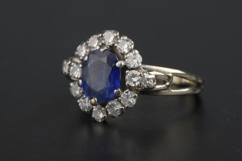 Ring in 18k white gold and 850 thousandths platinum, adorned with an oval sapphire in a setting of round brilliant diamonds (grey and missing from some stones).
