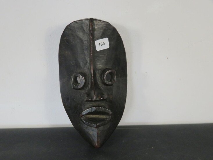 FACIAL MASK. Hard wood, beautiful shiny black patina. Round projecting eyes, lips spread apart, the nasal appendage is extended by a raised line to the top of the mask. Ivory Coast, Dan High 21 cm