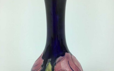 Moorcroft pottery slender neck vase decorated in the Magnolia pattern on blue ground, green painted signature to base, 21.5cm high