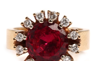 A ruby and diamond ring set with a round-cut ruby encircled by brilliant-cut diamonds, mounted in 14k gold. Size app. 52.