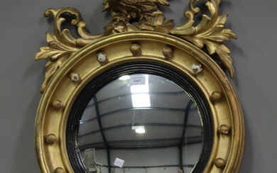 A 19th century Regency style giltwood and gesso framed circular convex wall mirror, carved with eagl