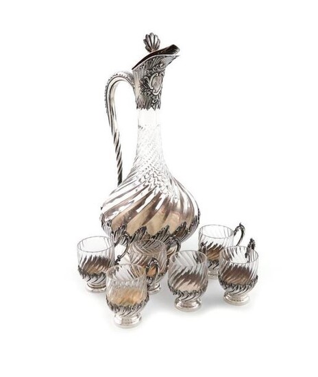 A French silver-mounted liqueur set, the ewer with maker~s mark of R.B in a lozenge, the cups by another maker, baluster form, swirl-fluted baluster form, the mounts with foliate and fluted decoration, on a circular foot, the hinged cover with a shell...