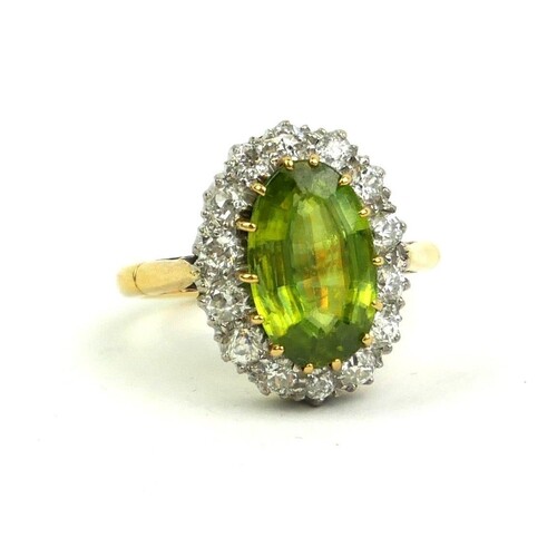 A YELLOW METAL, PERIDOT AND DIAMOND RING The oval cut centra...
