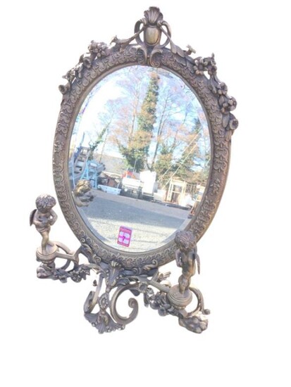 A brass dressing table mirror, the oval frame with...