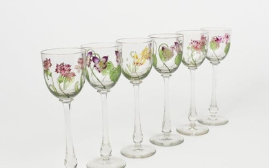 A set of six enamelled glass wine glasses the design attributed to Helen or Hannah Walton, the clear glass bowls enamelled with Art Nouveau violet, tulip, cornflower and cyclamen stems, the rim with thin gilt band, unsigned, 21.5cm. high (6)