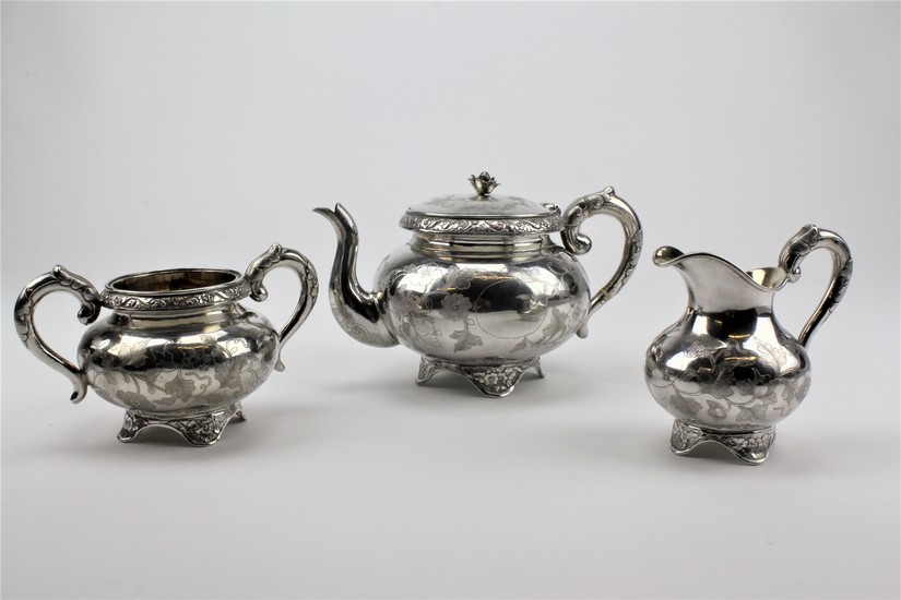 A three piece silver Chinese tea set with floral engraved 10...