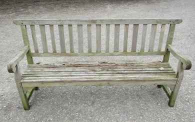 A well weathered teak garden bench with slatted seat and bac...