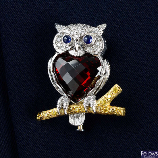 An 18ct gold diamond and garnet owl brooch, with sapphire eyes, perched on a 'yellow' diamond branch, by E. Wolfe & Co.