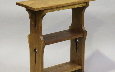 An Edwardian Arts and Crafts oak three-tier book table, the shaped sides pierced with stylized tulip