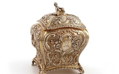 An electro-gilded tea caddy, circa 1900, rounded rectangular bombé form, with Rococo figures and foliate scroll decoration on a matted background, with a crest, the pull-off cover with a figural finial, on four scroll feet, height 13cm.
