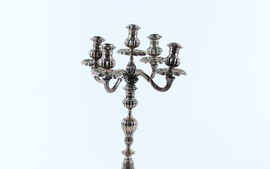 Candelabro a cinque fiamme in argento sbalzato e decorato a volute. Milano, secolo XX (g lordi 2400) (h. cm 40)…