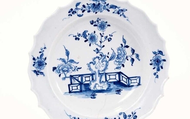 Lowestoft plate, with thickened and shaped rim, painted in blue with flowers and rockwork within a fenced garden, sprigs in the border, 22.2cm diameter