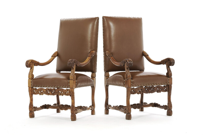 Paire de fauteuils de style Louis XIII, en noyer sculpté de feuilles d'acanthe, garniture en similicuir marron clouté, pieds réunis par u
