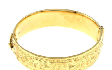 A 9ct gold engraved hinged bangle.