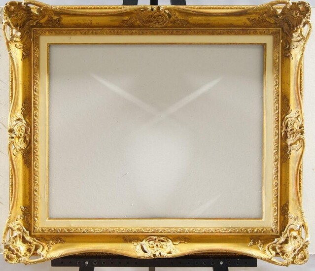 A Gilded Composition Louis XV Style Swept and Pierced Frame, mid-late 20th century, with leaf sight, the plain hollow with foliate scrollwork centres and shell cartouche corners, linked lozenge back edge, added parcel gilt and white painted slip...