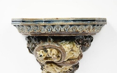 A Martin Brothers stoneware wall bracket designed by Robert Wallace Martin, dated 1878, modelled in relief with a dog-like creature biting its tail, with oak leaf and acorns, glazed in shades of blue, ochre and green incised R W Martin Southall, 1878...