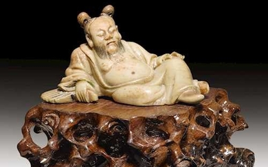 A SOAPSTONE CARVING OF A RECLINING SAGE.