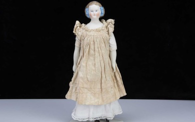 A late 19th century German bisque shoulder head doll with net snood and ribbons in hair