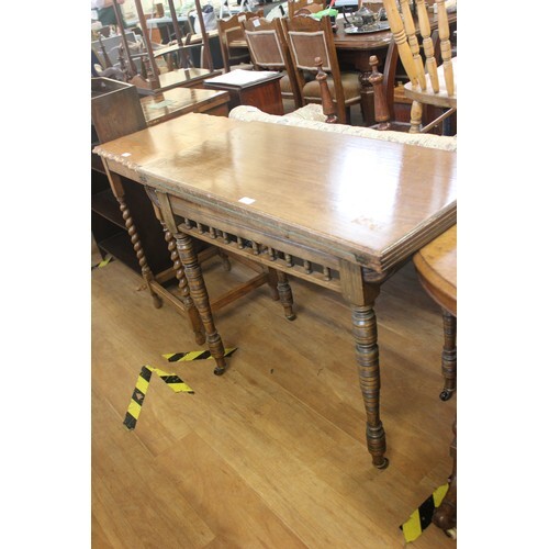 A late Victorian oak fold over swivel top card table, on tur...