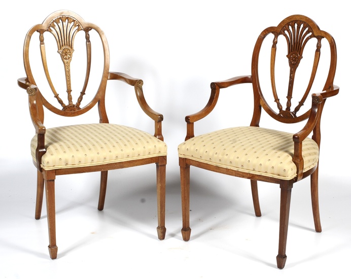 A pair of 20th century Hepplewhite style dining chairs. Each with trefoil shaped pierced foliate shield back, with striped stuffover seats, on square tapering legs and spade feet, 96cm high