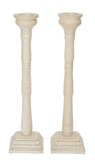 A pair of Anglo-Indian ivory candlesticks, Murshidabad, India, circa 1820, of tapered form, on rectangular bases rising with small bosses to a flaring bulbous head,29.21cm. (2)